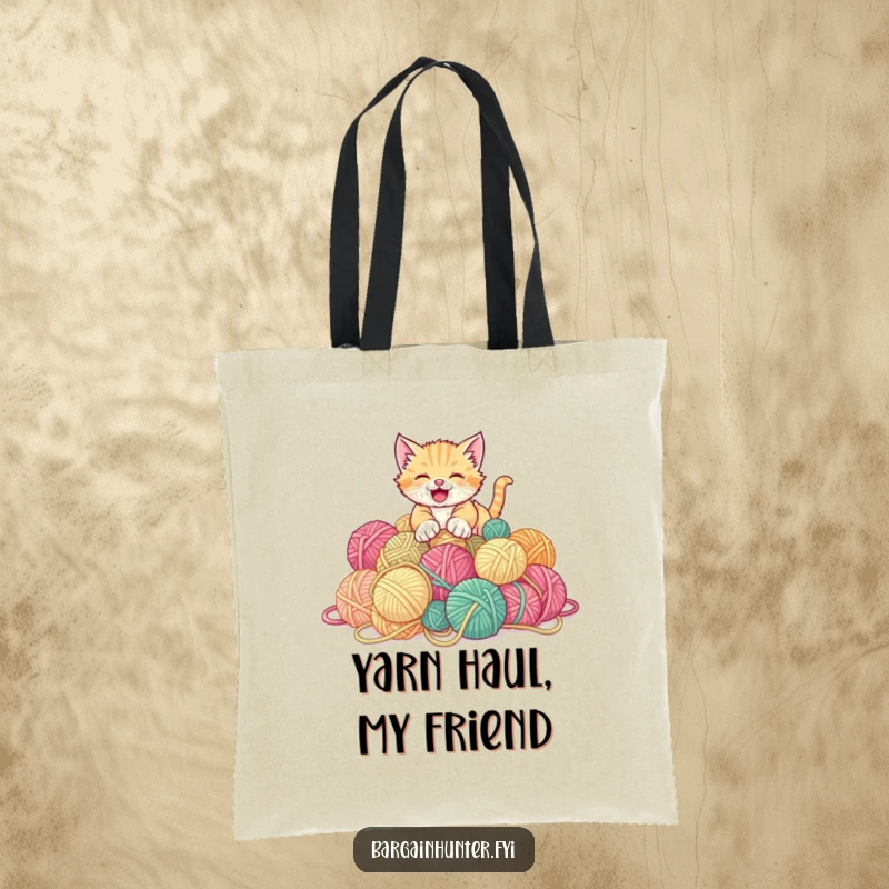 Funny kitten tote bag featuring a playful kitten gleefully pouncing on a big pile of discounted yarn balls.